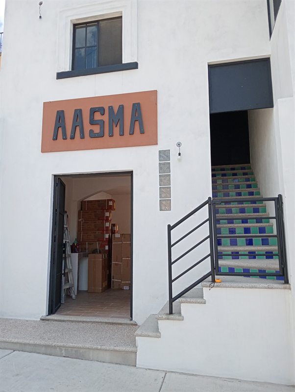 Fachada de la tienda AASMA con su letrero y equipos de aire acondicionado en la entrada